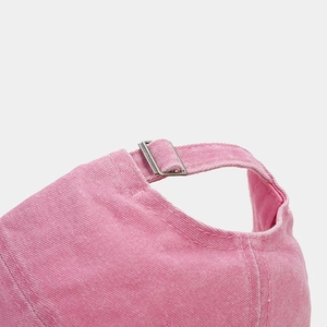Detail of adjustable metal buckle and vintage washed pink cotton texture on baseball cap