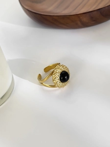 Close-up of vintage 18K gold-plated ring with natural round black stone on white fabric