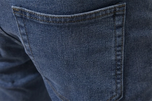 Detail view of denim jeans back pocket with blue wash texture and contrast stitching