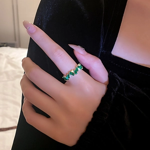 Bague raffinée plaquée or avec zircons verts rectangulaires sur la main d'un modèle