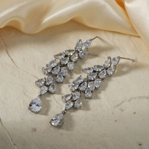 Detail of silver drop earrings with zircons on yellow satin and stone background