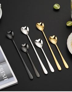 Flat lay of heart-shaped stainless steel spoons in black, gold, and silver finishes