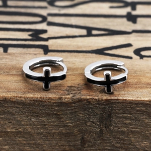 Sleek silver stainless steel hoop earrings with black cross pendant on wooden background