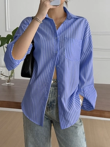 Detail view of women's blue and white striped button-down shirt with a front chest pocket