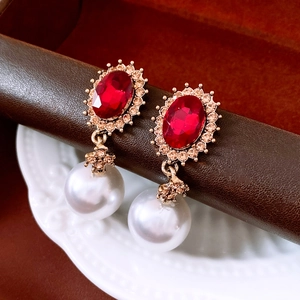 Macro shot of vintage gold earrings with red oval gemstone and large white pearl drops