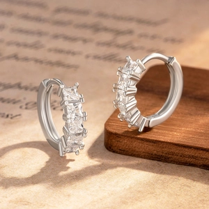 Silver round hoop earrings with five square zircon stones on vintage book background