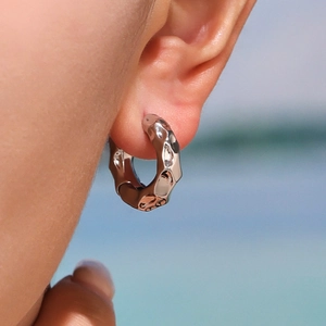 Boucles d'oreilles créoles en argent poli avec finition martelée portées par un mannequin