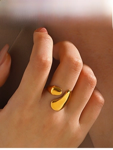 Macro view of golden liquid streamlined open ring with polished mirror finish and organic lines