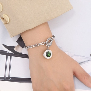 Detail of silver chain bracelet with green gemstone pendant and OT toggle clasp