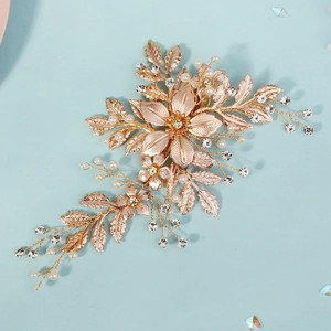 Handmade gold flower hair clip with pearls and rhinestones on a blue background