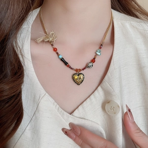 Macro shot of heart cross pendant and multicolored beads on vintage gold necklace