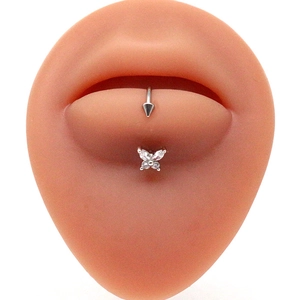 Close-up of stainless steel butterfly belly button ring on a silicone skin model