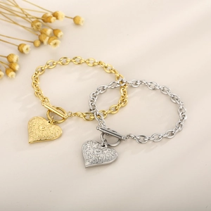 Detail of gold and silver OT buckle bracelets with floral engraved heart pendants