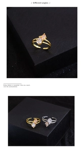 Detail of two-tone teardrop zircon rings with gold and silver finishes on a black display