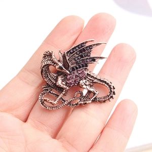 Detailed macro view of a vintage dragon brooch with purple rhinestones on a hand