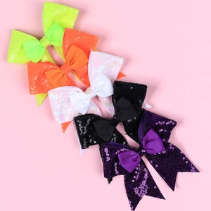 Detail view of five sequined bow hair clips in neon green, orange, white, black and purple
