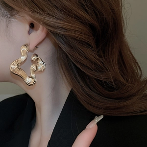 Close-up of gold irregular wavy earrings with textured liquid metal finish on model