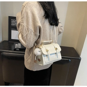 Detail of vintage beige crossbody bag with gold buckles and fluffy ball pendant charm