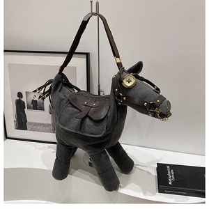 Macro shot of horse-shaped canvas bag showing grey denim texture and brown leather details