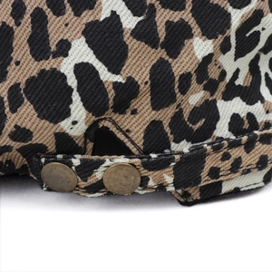 Close-up of leopard print fabric texture and antique bronze metal rivets on the beret