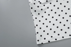 Detail of white polka dot fabric on summer top with precise double-needle stitching
