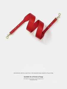 Macro detail of red smooth leather shoulder strap with adjustable golden metal buckles