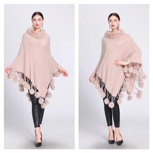 Detail of knitted poncho featuring faux rabbit fur collar and fuzzy pom-pom tassels