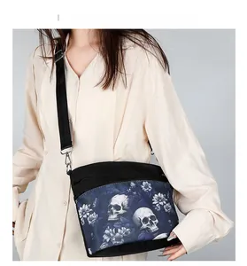 Detail of gothic skull and floral print on black crossbody bag with adjustable strap