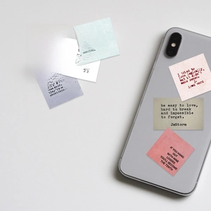Macro detail of vintage motivational quote stickers applied on a silver smartphone case