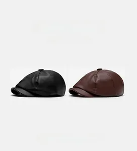 Detail view of black and dark brown faux leather newsboy caps with lychee grain texture