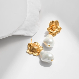Barockperlenohrringe mit goldenem Blumendesign auf künstlerischem Steindisplay
