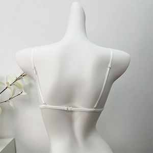Detail of white lace bra featuring ultra-thin straps and back clasp on a mannequin