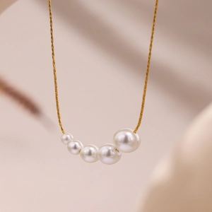 Minimalist gold necklace featuring five graduated pearls in a graceful crescent design