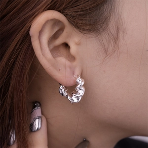 Close-up of polished silver hollow geometric U-shaped hoop earring worn by a model