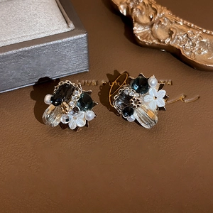 Close-up of crystal flower earrings with dark stones and pearls on leather background