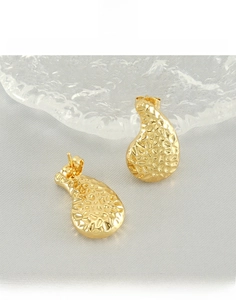 Macro shot of gold hammered teardrop earrings made of durable titanium steel texture