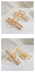 Macro shot of two glossy gold hollow metal hair claws on a minimalist background