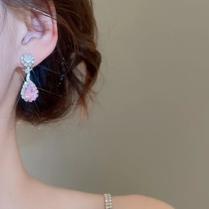 Close-up of pink teardrop zircon earrings with silver floral diamond settings on model