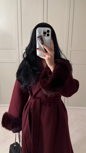 Detailed view of burgundy wool coat with luxurious faux fur cuffs and matching waist belt