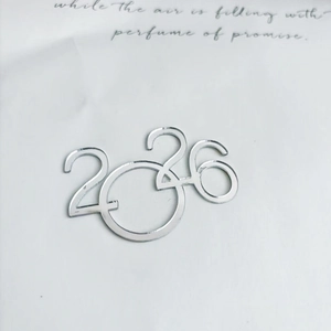 Close-up of shiny silver mirror acrylic 2026 topper for New Year cake decorations