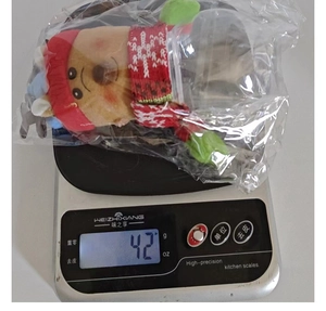 Detailed view of plush Christmas candy jar figurine being weighed at 42g on a scale
