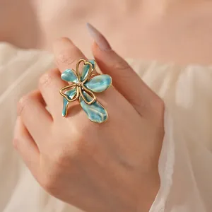 Vintage gold-plated flower ring with blue-green enamel petals worn by a model
