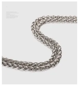 Macro shot of a polished silver wheat-patterned metal chain with detailed weaving
