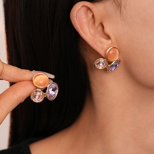 Boucles d'oreilles clous en pierre oeil-de-chat colorée sur un modèle féminin