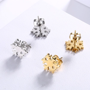 Golden and silver stainless steel snowflake stud earrings set on white surface