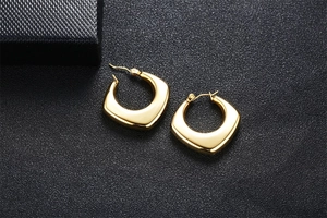 Close-up of golden hollow square hoop earrings in polished stainless steel for women