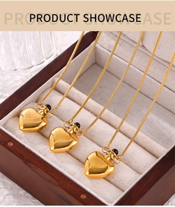 Detail view of heart-shaped gold pendants with snake chains in a wooden jewelry box