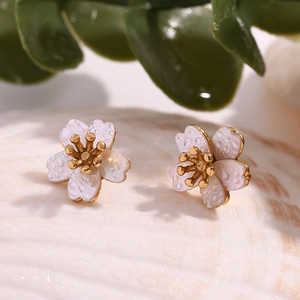 Macro detail of cherry blossom stud earrings with pearl white petals and gold pistils