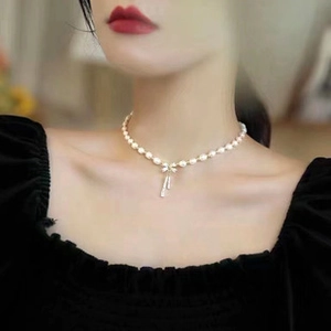 Detail of s925 silver necklace featuring a pearl bow pendant with hanging tassels