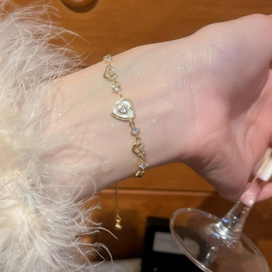 Macro detail of gold adjustable heart bracelet with zircon stones on female wrist